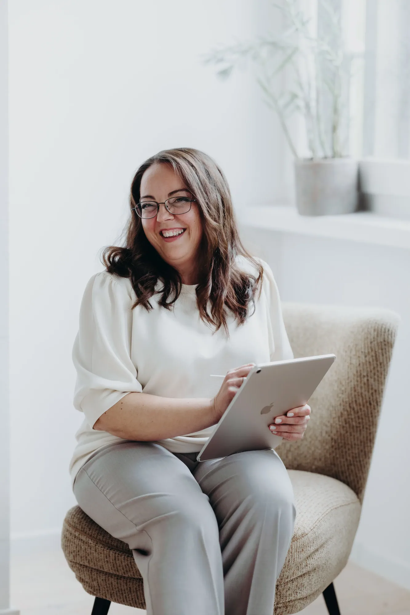 Marina Lübcke sitzt lachend in einem Sessel und hält ein Tablet