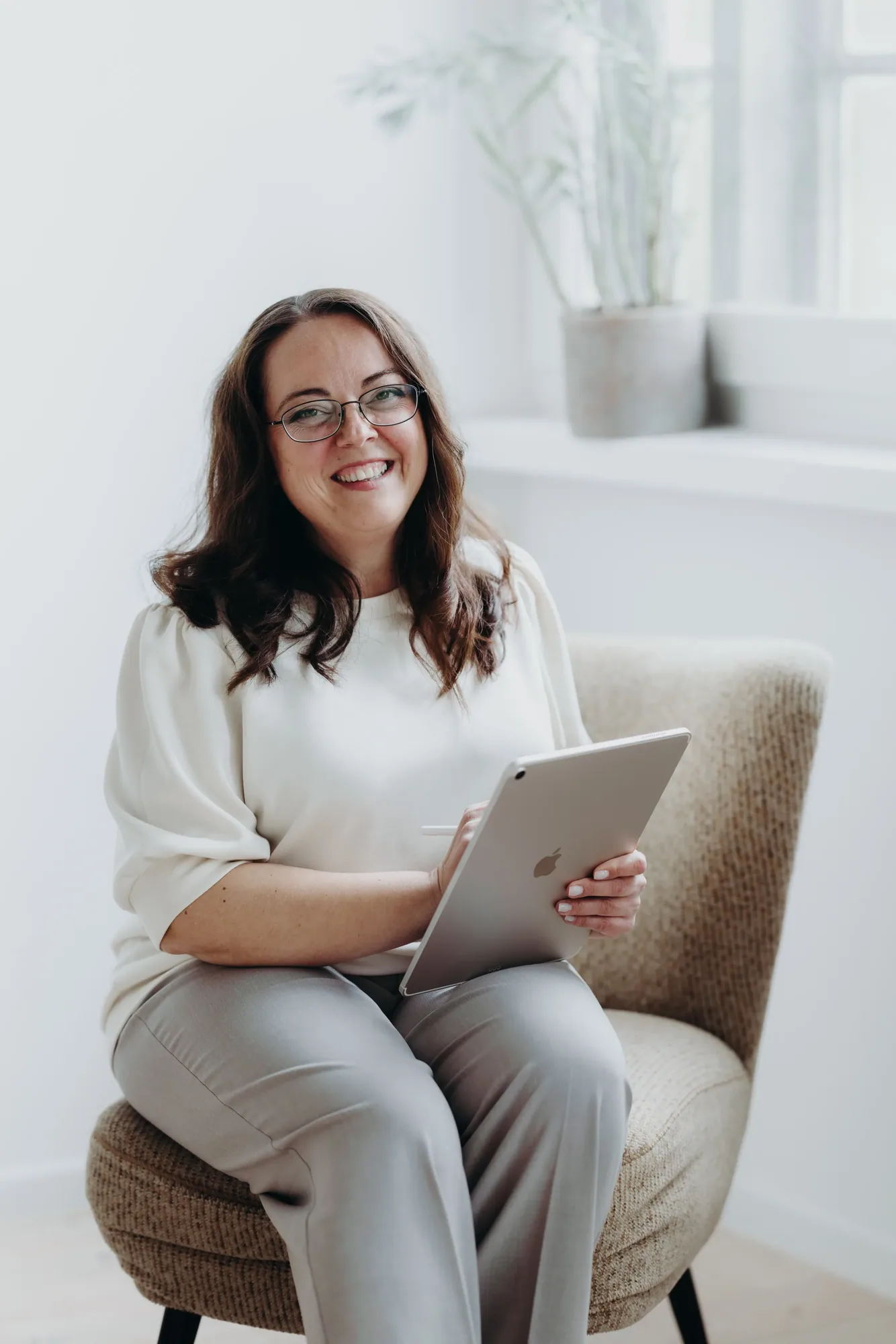 Marina Lübcke sitzt mit einem Tablet im Sessel und lächelt