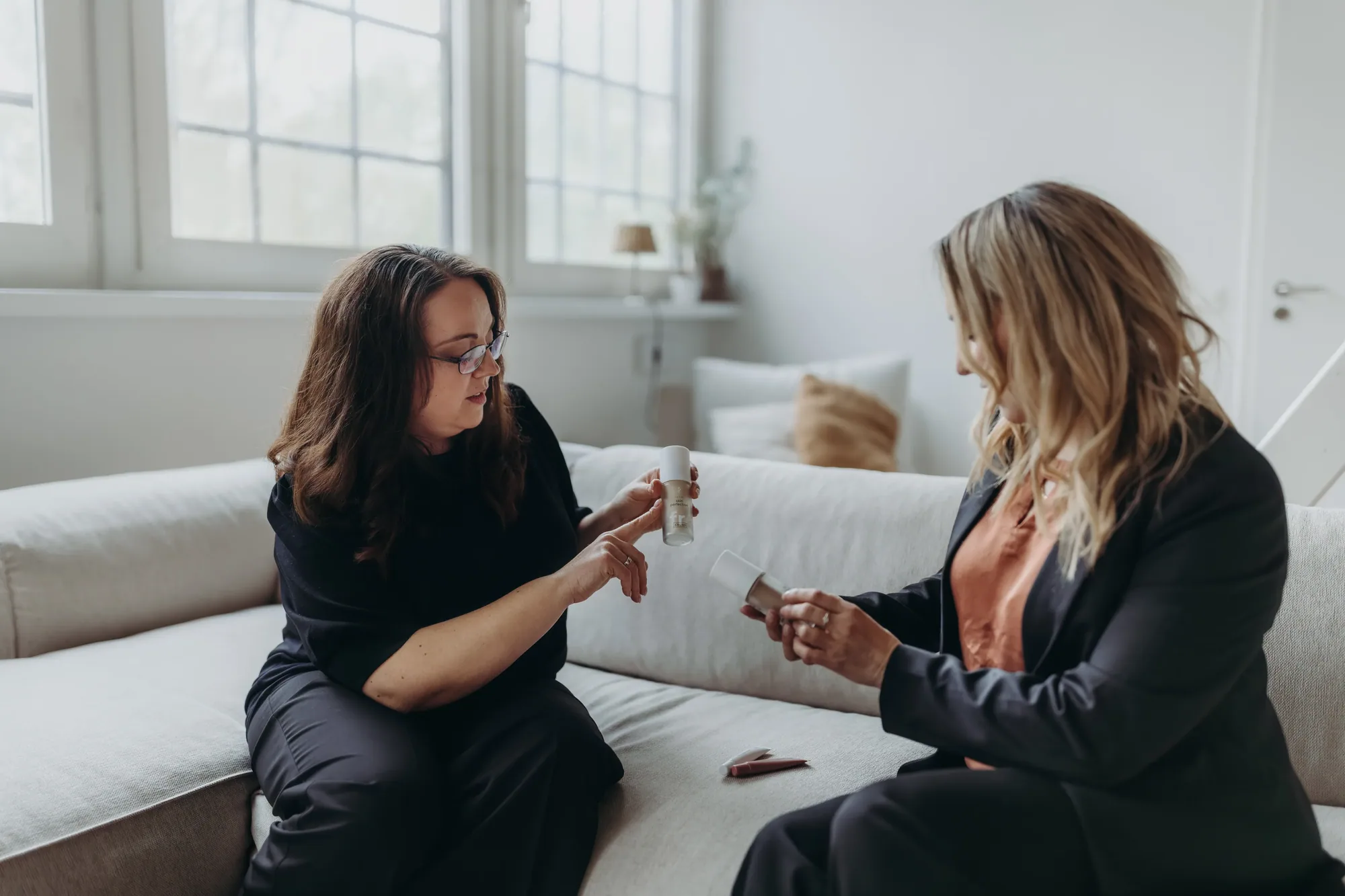 Marina Lübcke und eine Kundin sitzen auf dem Sofa und schauen sich Produkte an