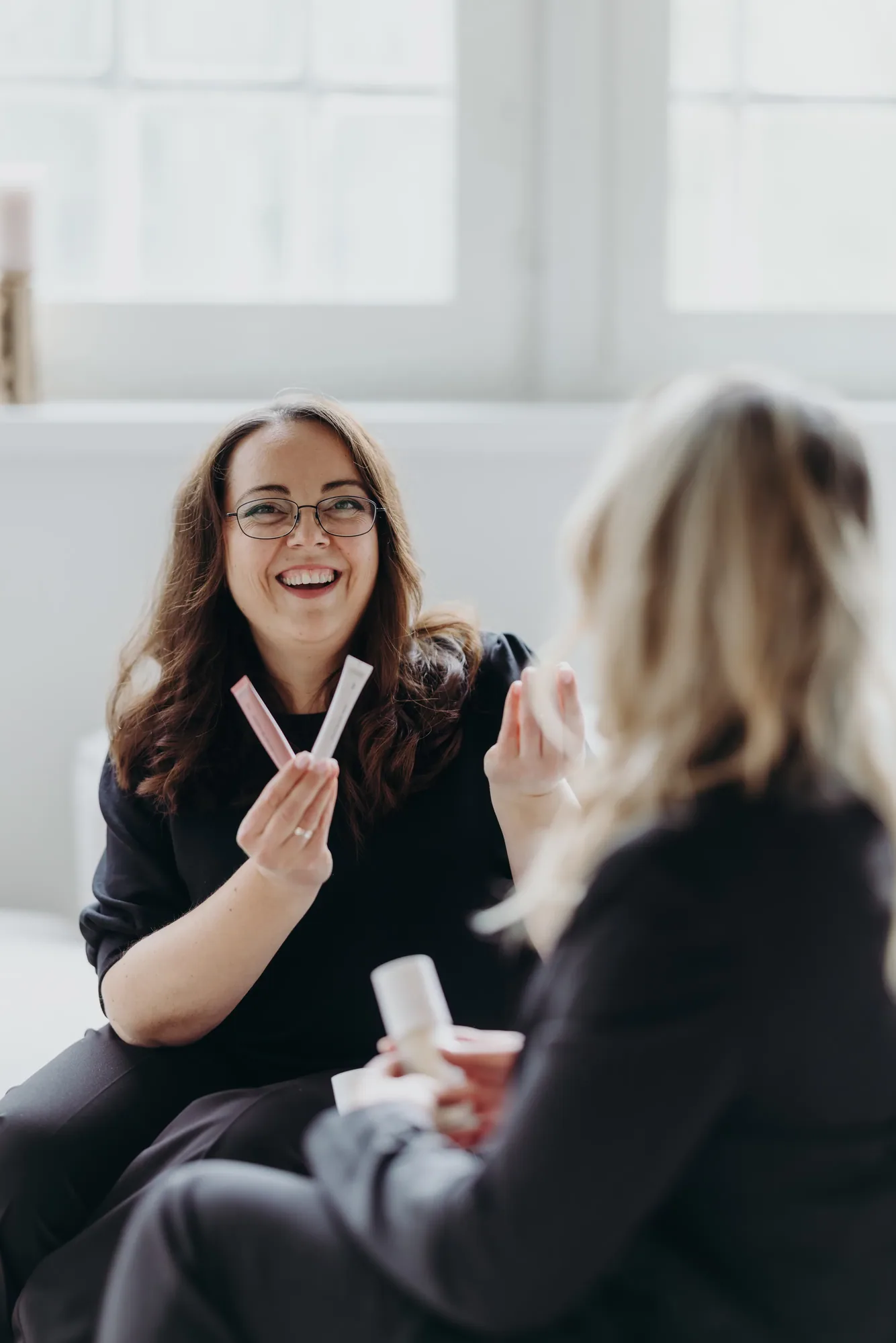 Marina Lübcke lacht während eines Beratungsgesprächs und hält zwei Produktproben in der Hand